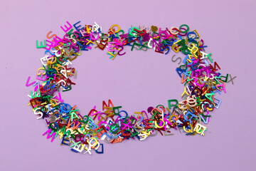 Bright multicolored small letters scattered on purple background Narrow focus line, shallow depth of field