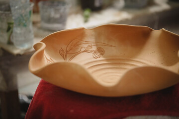 Ceramic bowl with intricate design on red cloth in pottery studio