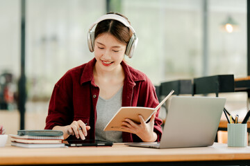Beautiful Asian female student studying online and taking notes Female accountant makes annual financial and tax reports.