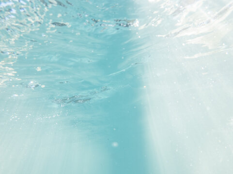rays of light filtering down through bubbly blue water shot from underwater