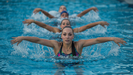 Woman splashes water during a synchronized swimming routine