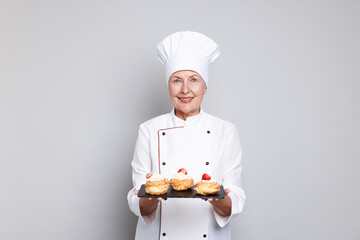 Professional pastry chef with choux on light grey background