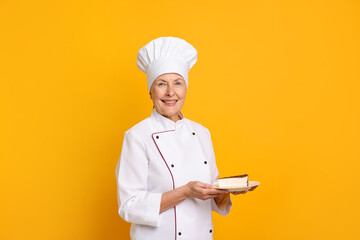 Professional pastry chef with piece of cake on orange background