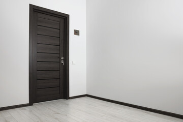 Empty renovated room with white walls and black door