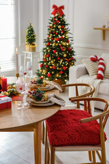 Christmas table setting with stylish dishware, glasses and burning candles in festive decorated room