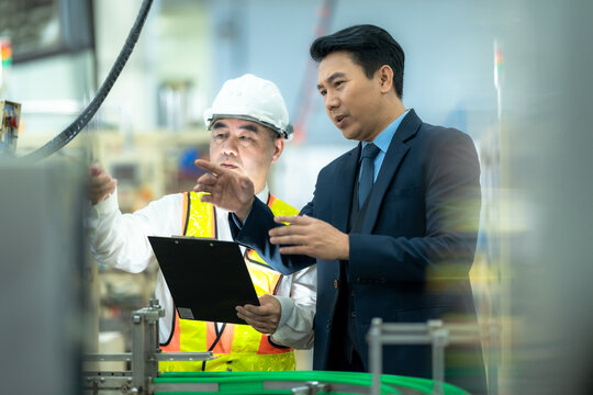 Asian team of engineers and factory supervisors are inspecting the production line in a factory that produces industrial products such as electronics, food, packaging in a modern factory.