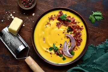 Autumn pumpkin soup with smoked bacon in a clay bowl . Top view with copy space.