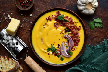 Autumn pumpkin soup with smoked bacon in a clay bowl . Top view with copy space.