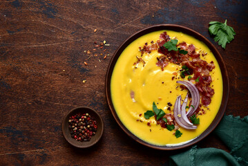 Autumn pumpkin soup with smoked bacon in a clay bowl . Top view with copy space.