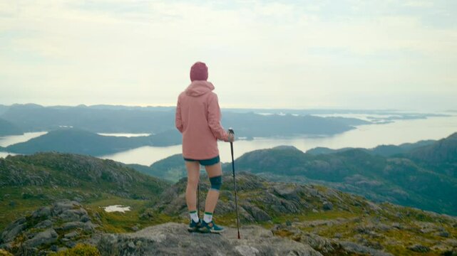 Woman hiking through Norway fjords. Experience the beauty of trails, dramatic scenery, and solo exploration by conquer the mountain. 4K handheld tracking zoom in shot