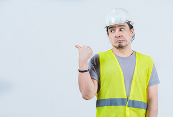 Funny construction worker pointing at an isolated blank space. Surprised builder pointing at an isolated advertising space