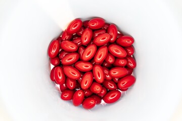 Red pills and supplements inside white jar