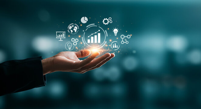 Hand holding glowing business analytics icons with graph and chart on a blurred teal background