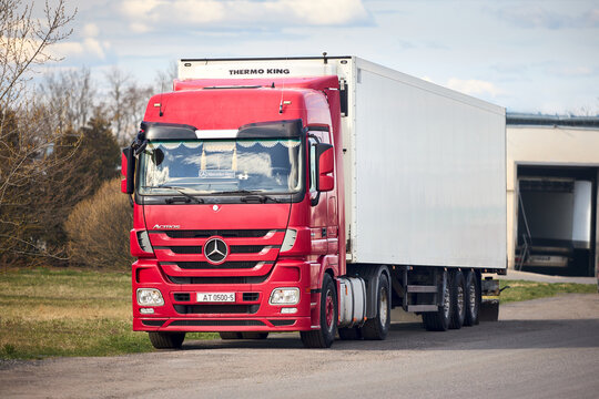 Mir, Belarus - April, 7 2025: Mercedes-Benz Actros 1846 red cabin cargo truck with refrigerator parked near large mall loading dock or loading bay with bumpers, levelers, lift, dock seals or shelters