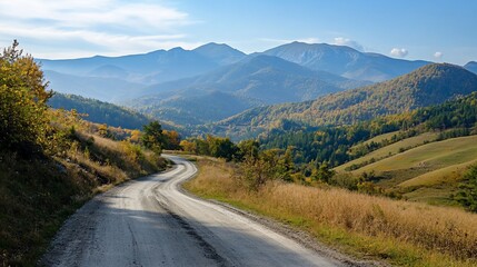 Naklejka premium Scenic mountain road winding through an autumnal landscape on a sunny day