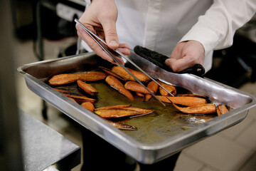 Cropped unrecognizable person getting tray with honey glazed carrots out of oven