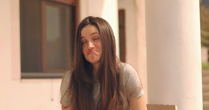 Need to think! Pensive doubting woman shrugging shoulders and imagining in mind, wondering difficult solution, feeling confused, not sure about choice. Girl sitting outdoor near house.