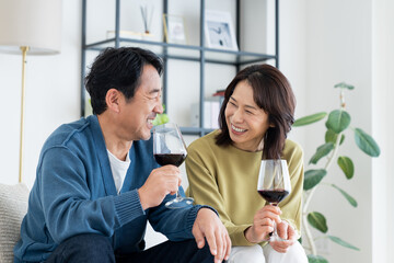 リビングでワインを飲むミドルの夫婦