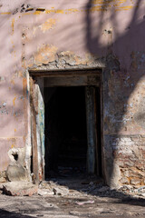 Abandoned doorway revealing dark interior of a derelict building with peeling paint and crumbling...