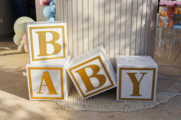 Gender Reveal Party Decorations with Boxes That Spell Out the Word Baby


