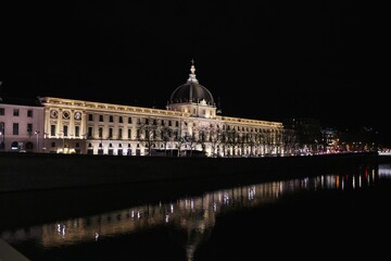 Fototapeta premium Building in Lyon France illuminated at night with reflections on Rhone River