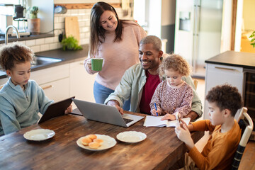 Family doing homework and remote work together in kitchen at home