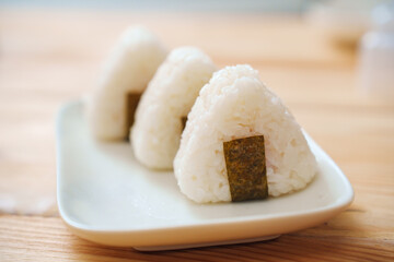 Onigiri made of rice and nori seaweed are spun on a white plate.