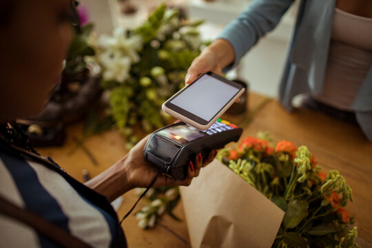 Customer making contactless payment with smartphone at flower shop counter