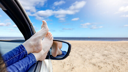 Legs sticking out of car window on the beach - summer road trip lifestyle. Empty space for branding...