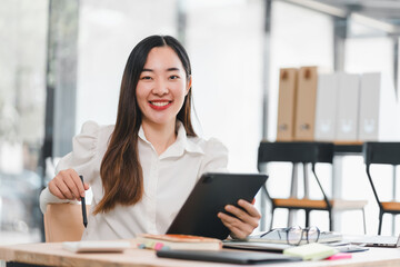 Young woman smiling tablet office casual business Asian technology workspace desk glasses notebook pen modern professional