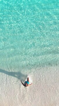woman runs enters into the tropical beach water at sunset on white sand, surrounded by calm waves and soft golden light, summer vacation, traveling, family resort, happiness