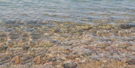 Clear waves on pebbles and rocks. Tropical summer nature landscape pattern