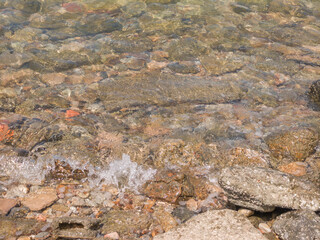 Clear waves on pebbles and rocks. Tropical summer nature landscape pattern