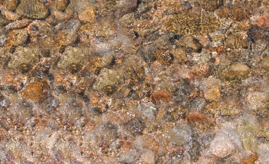 Clear waves on pebbles and rocks. Tropical summer nature landscape pattern