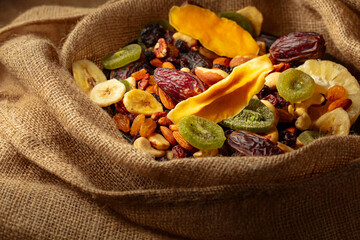 Dried tropical fruits and nuts in burlap bag.