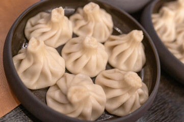 Steamed khinkali dumplings served on a black plate, georgian cuisine