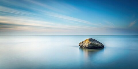 Serene coastal scene featuring a solitary rock in calm, clear water under a tranquil sky