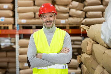 A smiling male worker poses confidently in a warehouse setting, promoting a message of safety,...