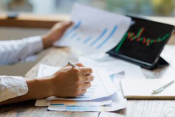 Focused on strategy, an investor holds a market analysis report, assessing stock performance with a...