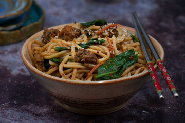 Korean kimchi and seitan fried noodles in bowl with chopsticks, copy space