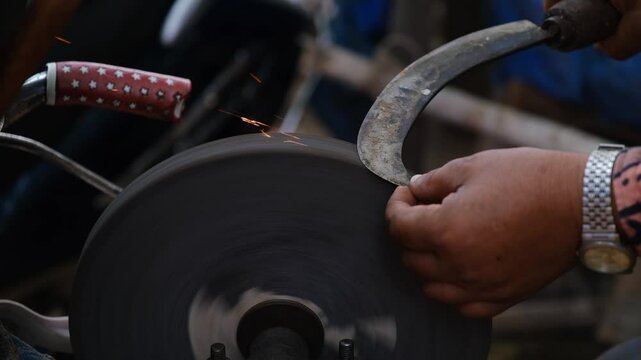 Close-up of Traditional Knife Sharpening by Hand on a Rotating Sharpening Stone in India, Sparks Flying as Blade is Sharpened