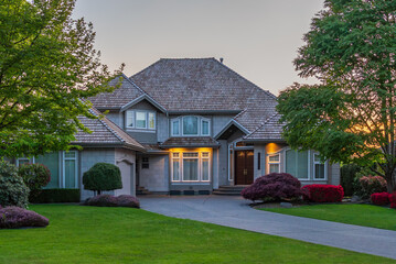 Obraz premium Two story stucco luxury house with nice Spring blossom landscape at night in Vancouver, Canada, North America. April 2025.