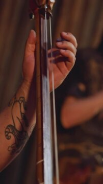 Musician plays string instrument with long thin neck groupmate taps drums in traditional cabin closeup. Festival of mystical Altai music. Folk band