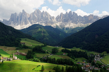 Summer scenery of idyllic Val di Funes with rugged peaks of Odle mountain range in background and a church in Santa Maddalena Village in the green grassy valley in Dolomiti, South Tyrol, Italy, Europe