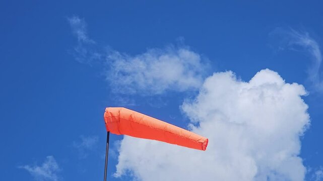  the orange windsock on a pole in strong wind against a blue sky Airbag, wind direction, know which way the wind is blowing