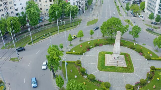 Establishing aerial footage of city streets with traffic and a monument on a roundabout