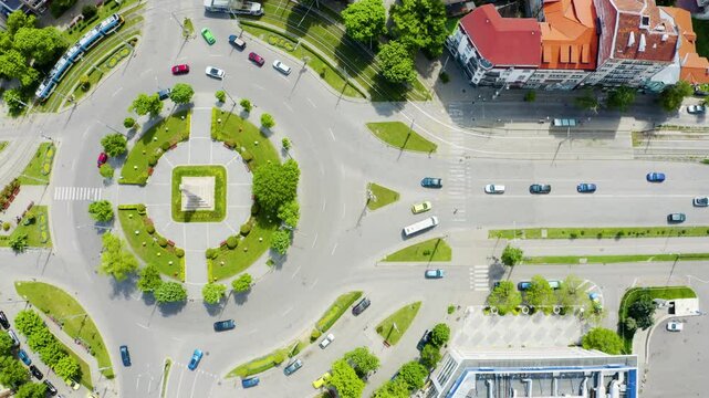 Establishing aerial footage of city streets with traffic and a monument on a roundabout