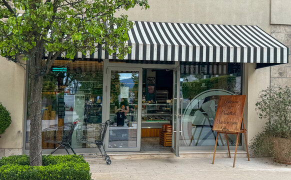 Entrance to PORTOKALI Cafe with striped awning and outdoor seating. Healthy lifestyle concept.Porto Montenegro