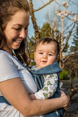 Little baby girl and her mother walking outside during sunset. Mother is holding her baby,...