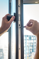Professional worker adjusting installed window with screwdriver